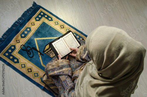 Murais de parede Muslim woman praying for Allah muslim god at room near window
