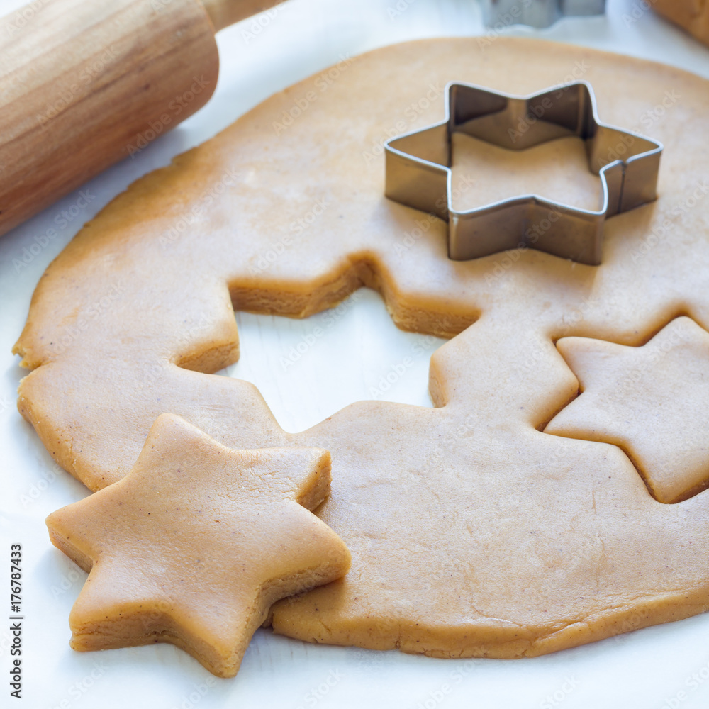 Making gingerbread cookies. Dough, metal cutter and rolling pen on a wooden table, square format Making gingerbread cookies. Dough, metal cutter and rolling pen on a wooden table, square format