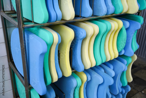 Colorful foam kickboards on silver metal rack by swimming pool photo