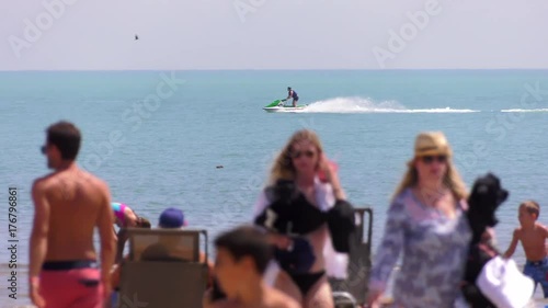 seadoo jetski races along water with beach crowd foreground 4k photo