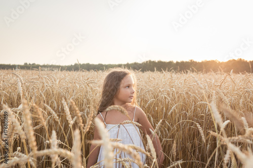 Little beautiful smiling girl on a gold wheat field walking at sunset. Happy five years old girl smiling and laughing in summer day at nature © 4frame group