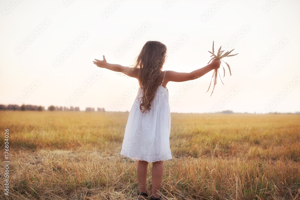 Little beautiful smiling girl on a gold wheat field walking at sunset. Happy five years old girl smiling and laughing in summer day at nature. Happyness freedom and carefree childhood concept Little beautiful smiling girl on a gold wheat field walking at sunset. Happy five years old girl smiling and laughing in summer day at nature. Happyness freedom and carefree childhood concept