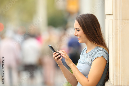 Side view of a girl checking a smart phone on the street