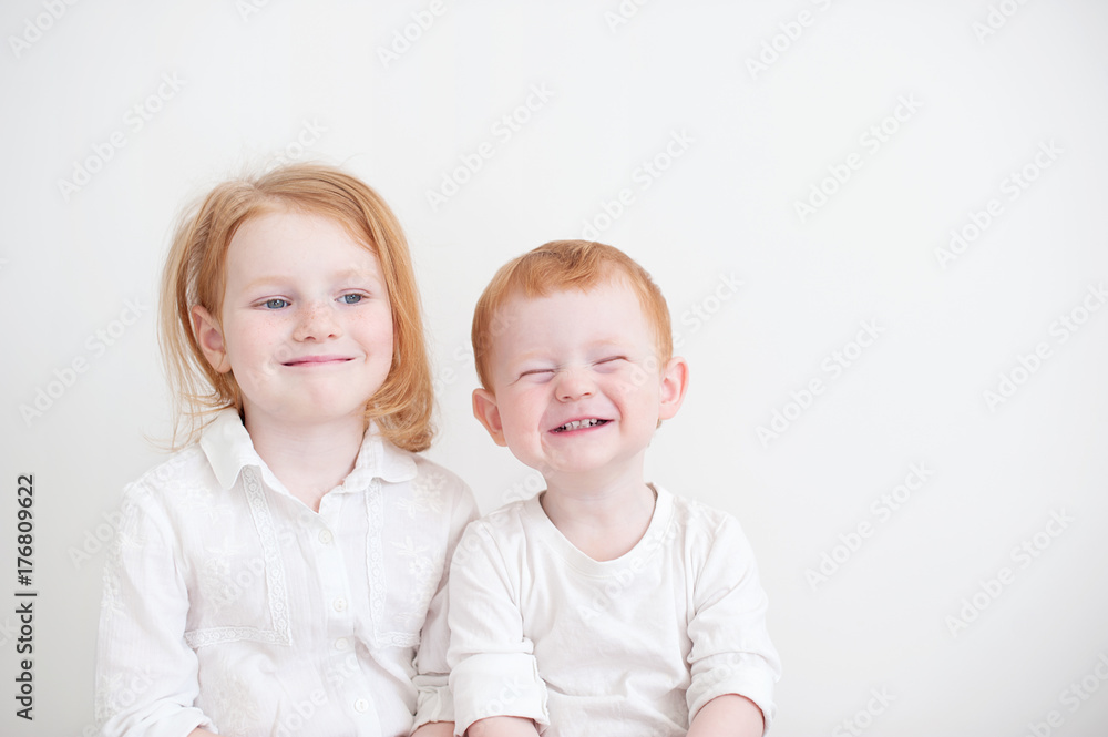 Funny brother and sister are sitting side by side