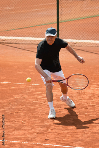 Active senior man playing tennis © Microgen