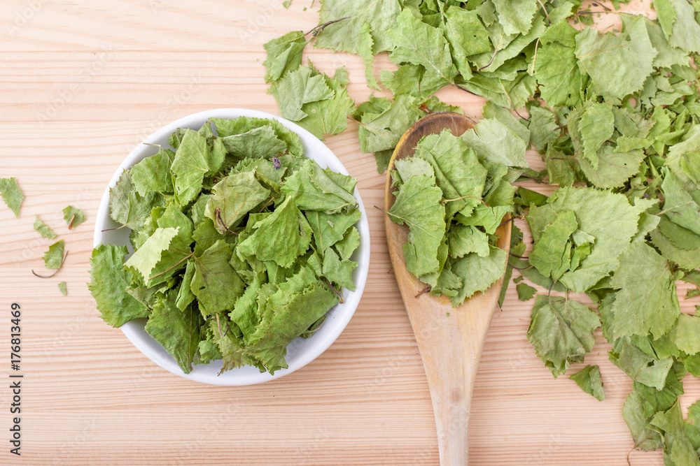 dried medicinal plant / Top view of dried birch leaves, spoon and bowl on a wooden background dried medicinal plant / Top view of dried birch leaves, spoon and bowl on a wooden background