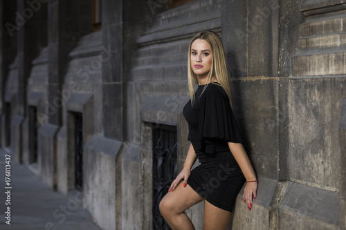 Young blonde woman wearing black dress on street