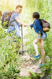 happiness couple hiking together in forest holding hands helping to climb up