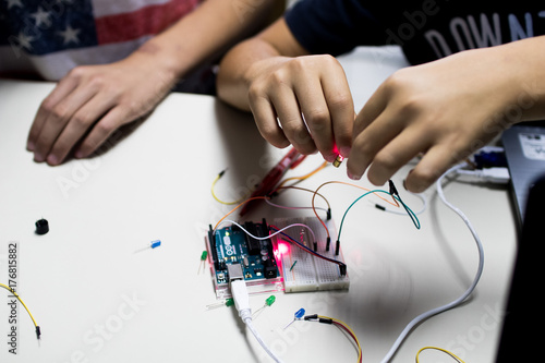 two children build a prototype circuit with a red laser controlled by a microcontroller. STEAM and coding activity photo