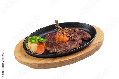 Isolated medium rare wagyu steak topping with mince carrot on hot plate and wooden plate served with potato salad.