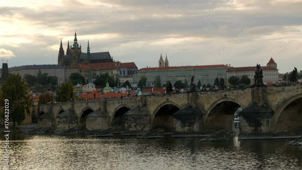 Early evening shot of tourist crossing the Charles Bridge in Prague with Prague Castle behind. Early evening shot of tourist crossing the Charles Bridge in Prague with Prague Castle behind.
