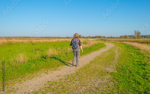 Woman walking in a field in sunlight at fall