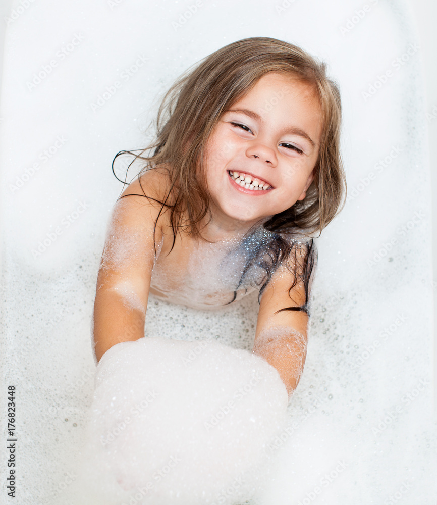 Happy little child girl is taking a bath with a foam Stock Photo