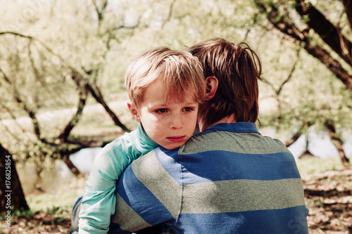 Sad crying son hugging father