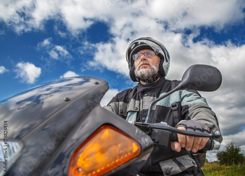 elderly motorcyclist wearing a jacket and glasses with a helmet