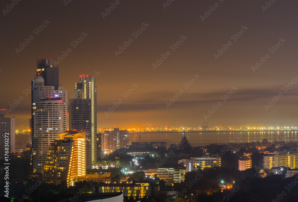 Night cityscape of skyline, tall buildings and cities near sea or river with gold and dark sky for copy space