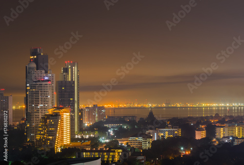 Night cityscape of skyline, tall buildings and cities near sea or river with gold and dark sky for copy space