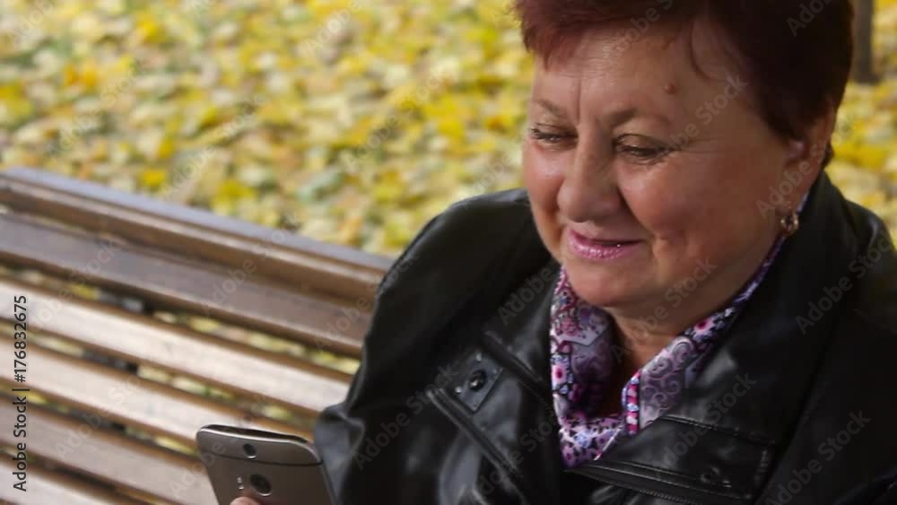 Elderly women with phone in autumn park. Elderly women with phone in autumn park.