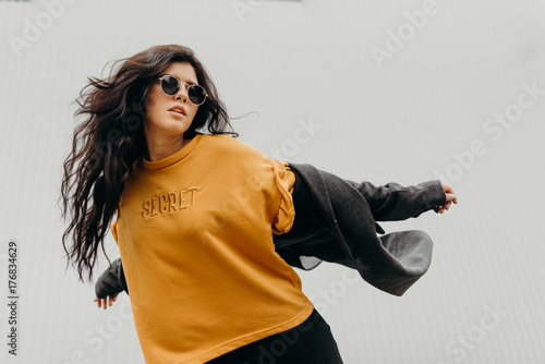 Portrait of stylish modern young curly woman in coat sunglasses photo