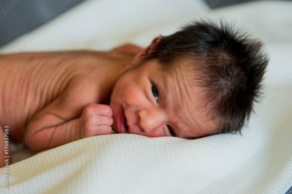 New born baby boy sleeping and smiling with opened eyes New born baby boy sleeping and smiling with opened eyes