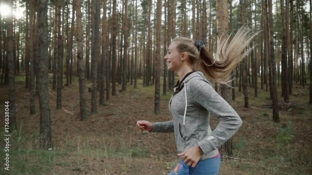 A girl runs along an asphalt road in a pine forest. A girl runs along an asphalt road in a pine forest.