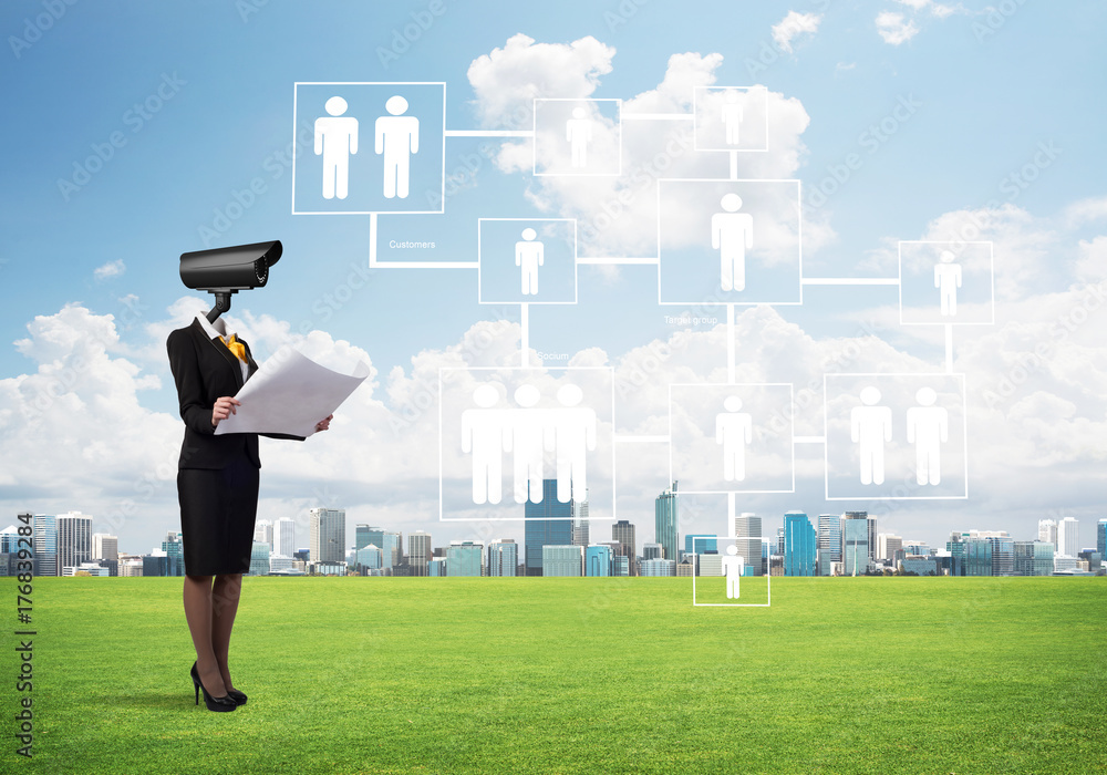 Camera headed woman standing on green grass against modern cityscape Camera headed woman standing on green grass against modern cityscape