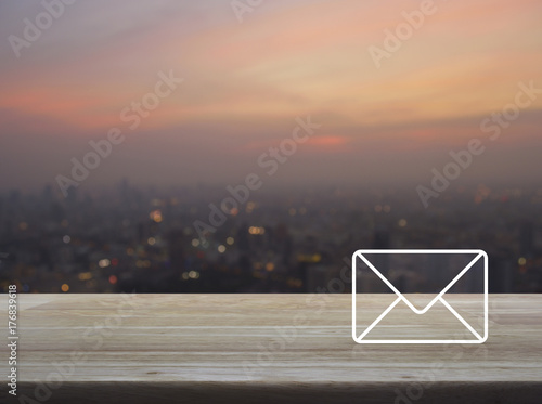 Mail icon on wooden table over blur of cityscape on warm light sundown, Contact us concept
