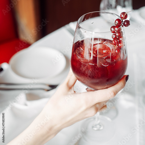 red cocktail with cranberries, glass in hand photo