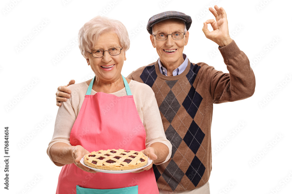 Elderly woman holding freshly baked pie and elderly man making ok sign Elderly woman holding freshly baked pie and elderly man making ok sign