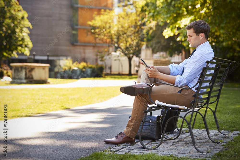 Fototapeta premium Businessman Outdoors Using Digital Tablet On Lunch Break In Park
