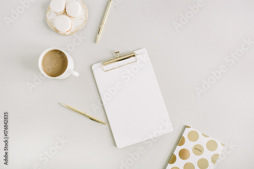 Modern home office desk with clipboard, macaroons, pen, coffee mug on pastel background. Flat lay, top view lifestyle concept.