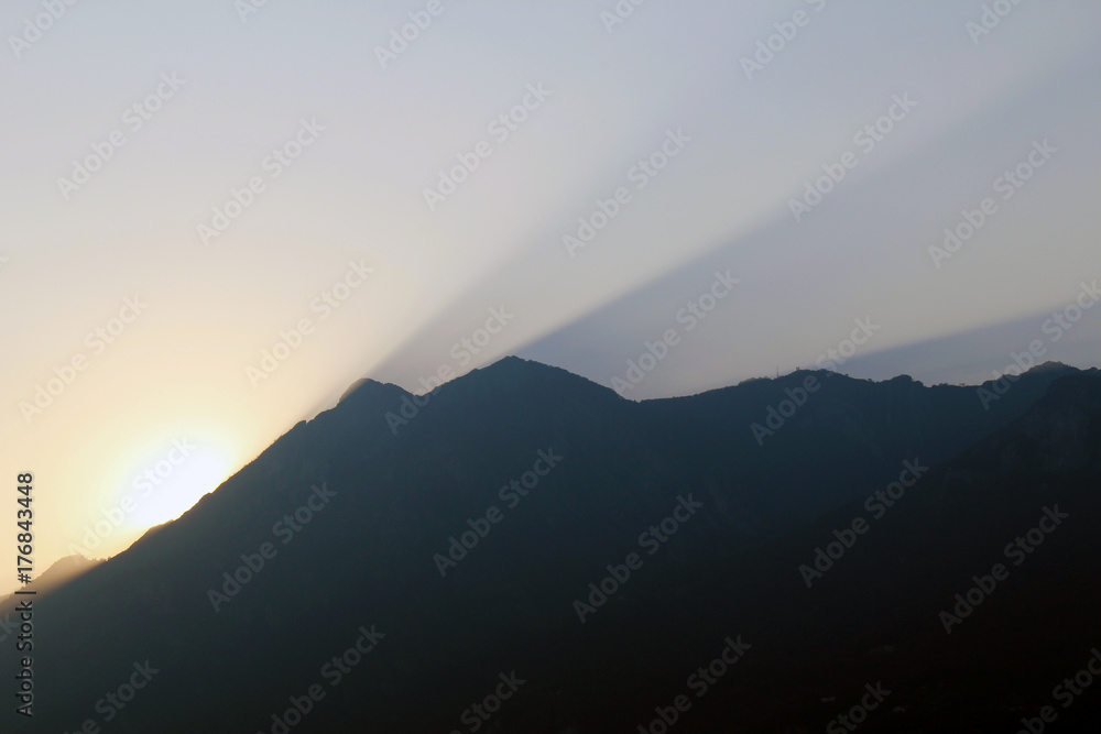 Sunset and rays of light in the sky from behind a mountain