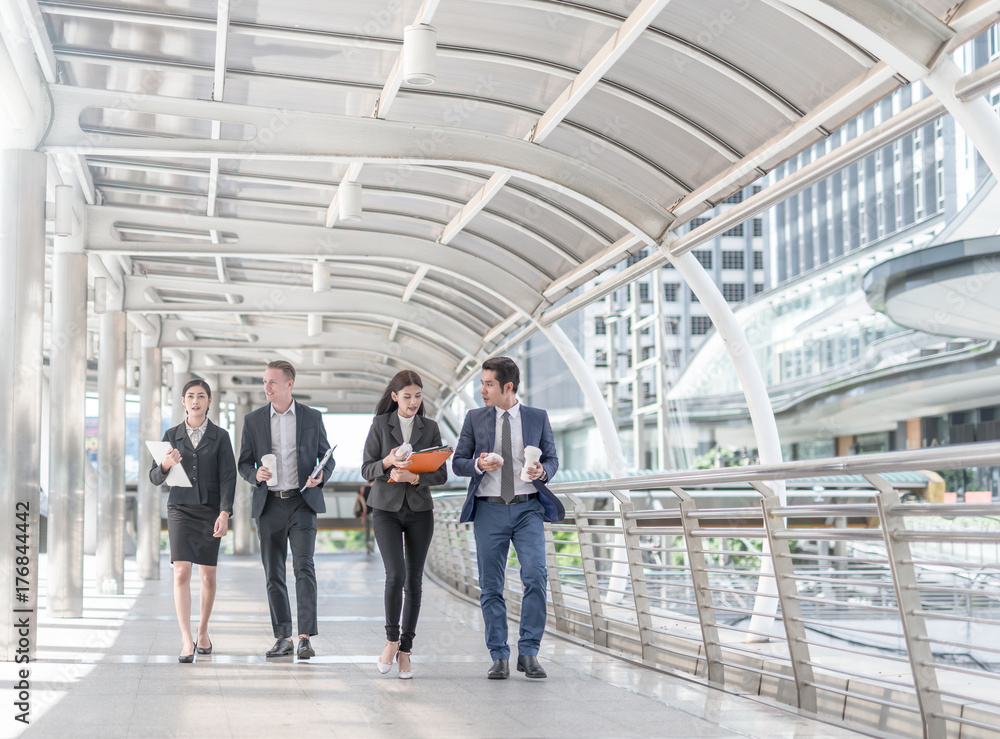 Happy Business colleagues walking outside office & talking to each other. Businessman walk talk and hold coffee cup