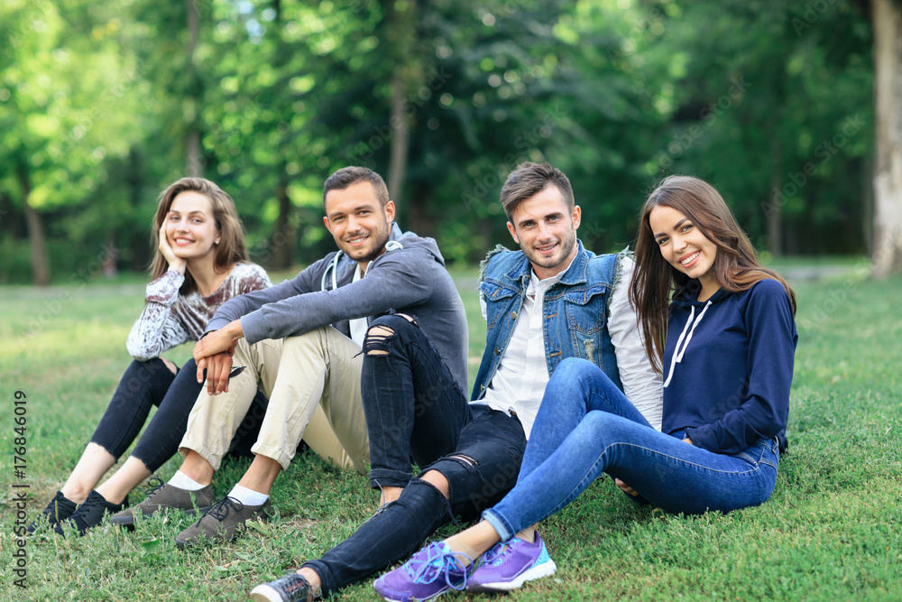 Young people sitting on grass in nature, looking at camera