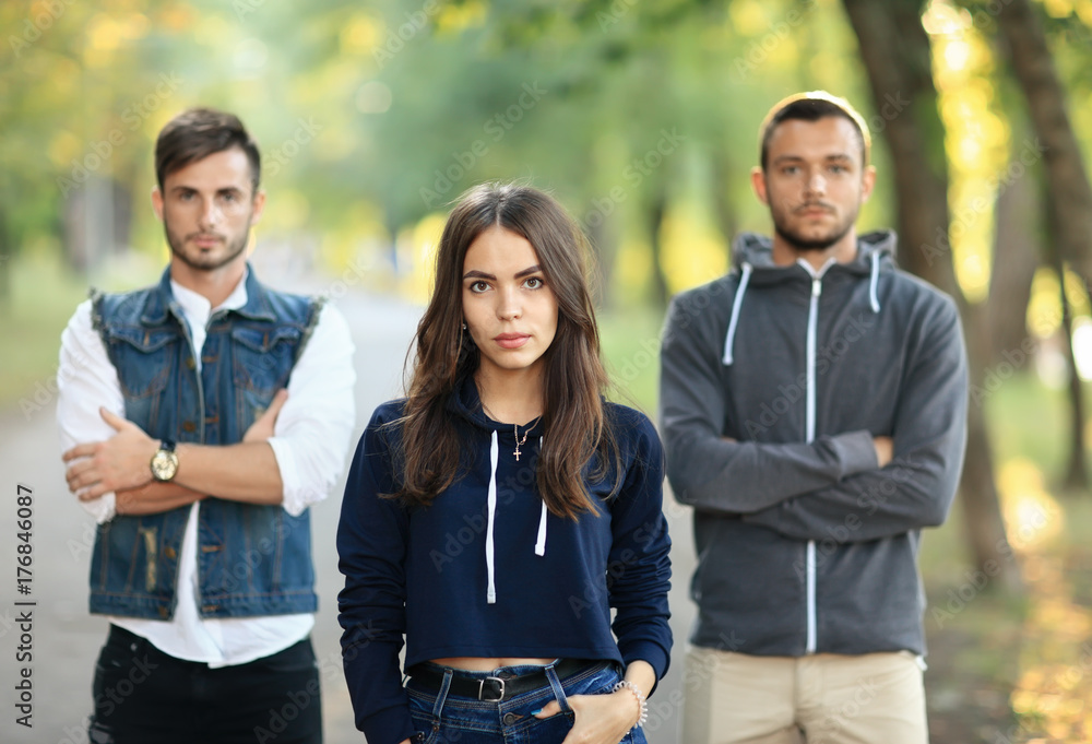 Fototapeta premium Beautiful young woman and two men behind her
