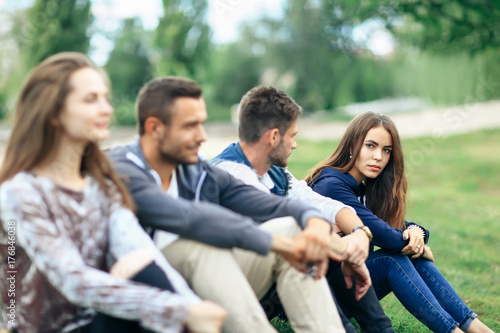 Young people sitting on lawn in park closeup