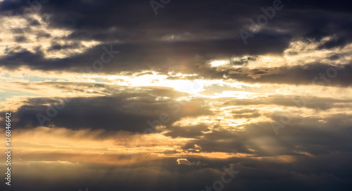 Astonishing view of sunset with dark clouds and golden sunbeams.