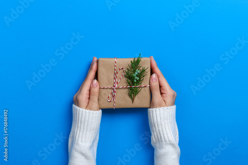 Female hands holding gift box on Blue background