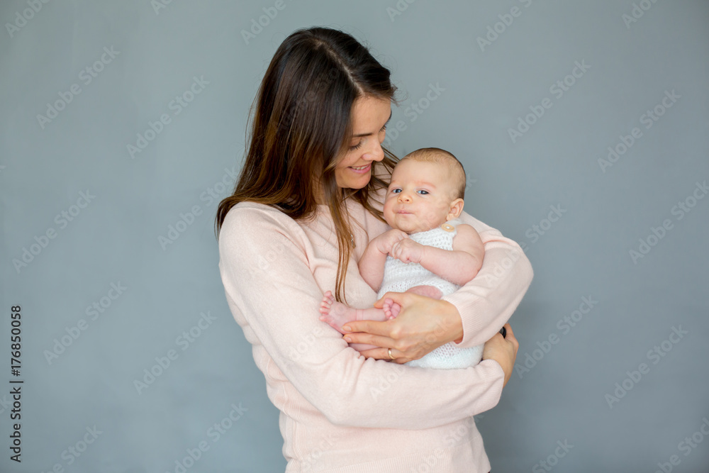 Young mother, caressing her newborn baby boy, holding him in her arms and smiling