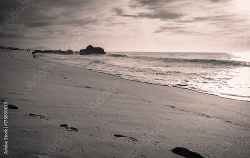 silhouette of people enjoying on sandy beach with waves hot sunny day in october on atlantic coast in black and white with red filter, capbreton, france photo