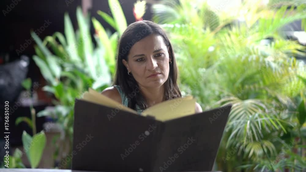Satisfied woman sitting in exotic restaurant and reading menu, steadycam shot
Satisfied woman sitting in exotic restaurant and reading menu, steadycam shot