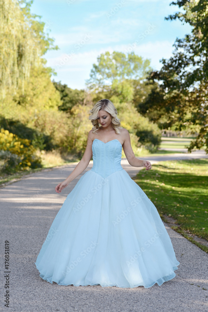 young woman in blue ball gown in garden