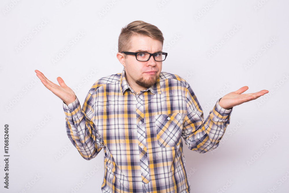 Confused young man dressed in shirt standing over white background gesturing hands. Confused young man dressed in shirt standing over white background gesturing hands.