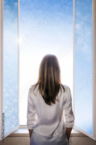 Woman opens the window on a cloudy sky, and light enters the room. A woman with long hair and shrugging as she opens the window doors to let the light into the room. Cloudy sky. Space for text. Free Download Woman opens the window on a cloudy sky, and light enters the room. A woman with long hair and shrugging as she opens the window doors to let the light into the room. Cloudy sky. Space for text. - GFXLoad