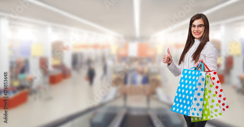 A woman is a buyer with a package of gifts on the background of a market, a shopping center.