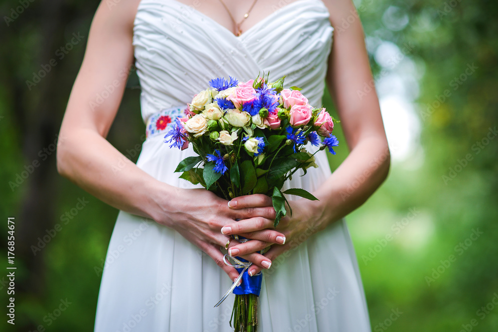 Beautiful wedding bouquet in hands of a young bride with a beautiful wedding manicure on nails.