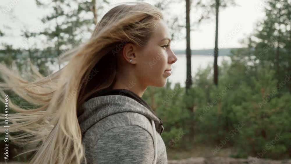 A runner runs through a pine forest. A blonde in a gray sports suit runs in the forest. A runner runs through a pine forest. A blonde in a gray sports suit runs in the forest.