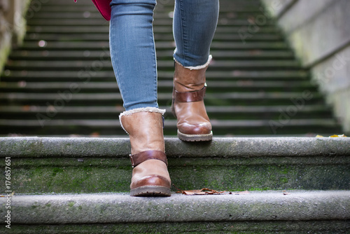 Girl wearing stylish fall leather boots. Woman feet walking down the stairs. 