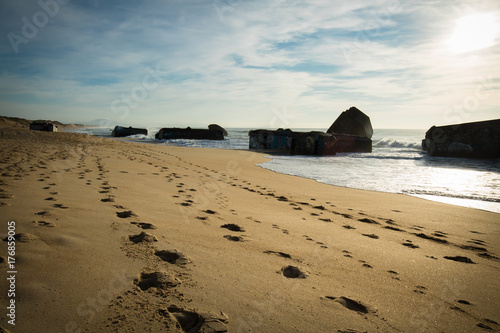 silhouette of war blockhouse on scenic beautiful sandy beach seascape with waves on atlantic ocean in blue sky in capbreton, france 