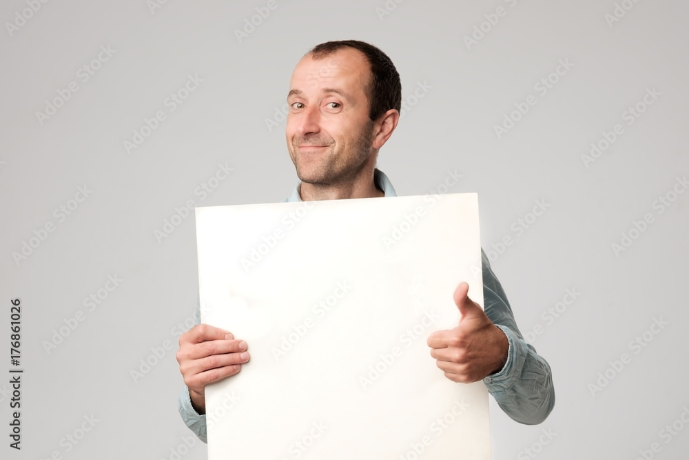 Hispanic man holds the blank sign in a studio white background. Hispanic man holds the blank sign in a studio white background.